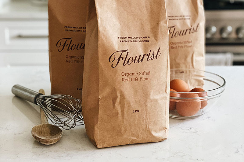 Three bags of Flourist-brand organic sifted fife flour on a table