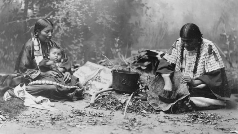 Indigenous couple with baby making porridge using hand-ground flour